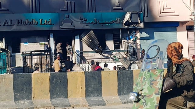 Commuters ride past a bank set ablaze by militants at Kalat district, in Pakistan's Balochistan province on February 1, 2025. Eighteen paramilitaries were killed and three others seriously wounded in an attack in Pakistan's southwest Balochistan province, police and the military said on February 1. (Photo by AFP)