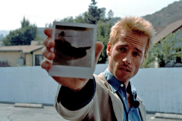 Guy Pearce holds up a Polaroid in a still from 'Memento' (2000).