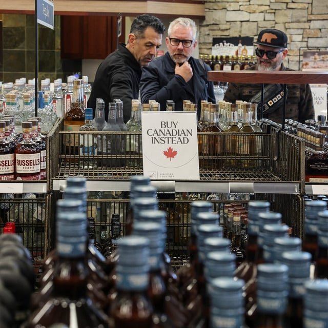 People look on as empty shelves remain with signs ''Buy Canadian Instead'' after the top five U.S. liquor brands were removed from sale at a B.C. Liquor Store, as part of a response to U.S. President Donald Trump's 25% tariffs on Canadian goods, in Vancouver, British Columbia, Canada, February 2, 2025. REUTERS/Chris Helgren