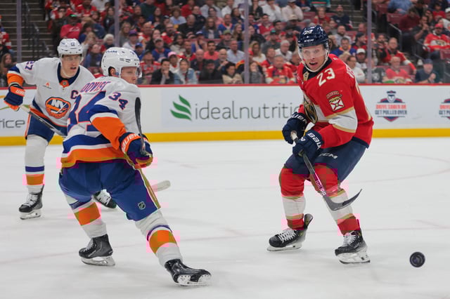 Feb 2, 2025; Sunrise, Florida, USA; Florida Panthers center Carter Verhaeghe (23) moves the puck as New York Islanders defenseman Adam Boqvist (34) defends during the second period at Amerant Bank Arena. Mandatory Credit: Sam Navarro-Imagn Images