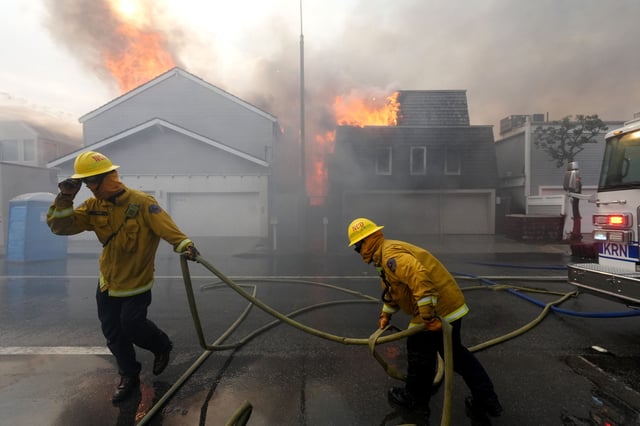 Fire crews doused several houses that caught fire along Pacific Coast Highway in Malibu on Wednesday, Jan. 8, 2025. Swept by powerful Santa Ana winds, the Palisades Fire erupted a day earlier and spread across Pacific Palisades and Malibu in north Los Angeles County.