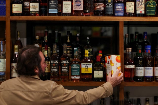 A liquor store worker places a bottle of Diageo's Crown Royal whiskey on a shelf in Los Angeles, California, U.S., December 4, 2024. REUTERS/Daniel Cole/File Photo