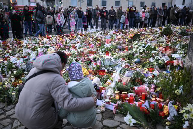 People look at flowers and candles on December 22, 2024, near a Christmas market in Magdeburg, Germany, where a man had driven a car into a crowd.