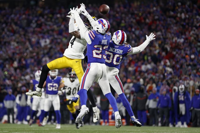 ORCHARD PARK, NEW YORK - JANUARY 15: George Pickens #14 of the Pittsburgh Steelers reaches for a pass against Dane Jackson #30 and Micah Hyde #23 of the Buffalo Bills during the fourth quarter at Highmark Stadium on January 15, 2024 in Orchard Park, New York.