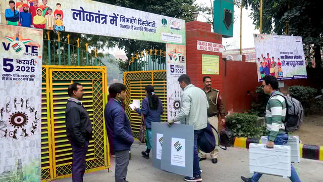 Polling officials carrying EVMs and other election materials arrive at a polling centre at Gole Market ahead of Delhi assembly election in New Delhi on Tuesday. 