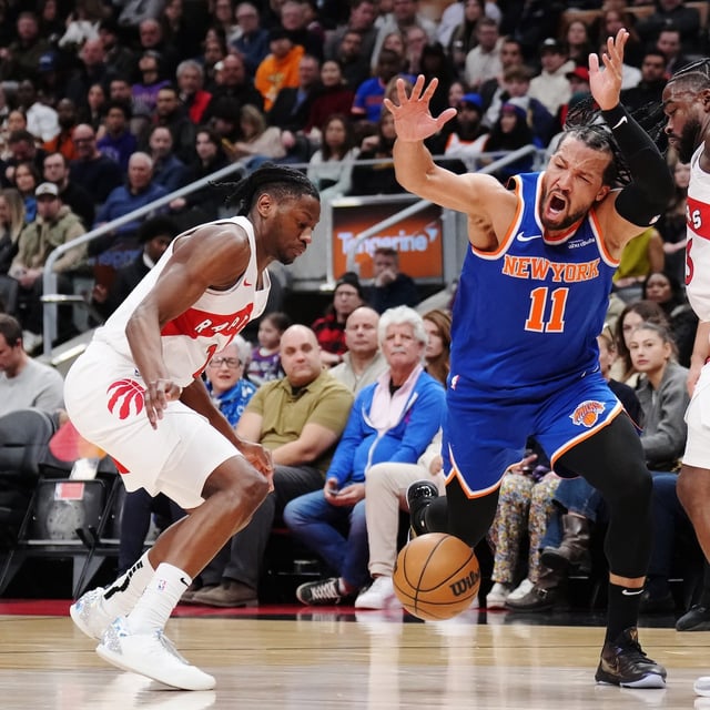 New York Knicks' Jalen Brunson (11) is fouled trying to get between Toronto Raptors' Jonathan Mogbo (left) and Jamal Shead (right) during second half NBA basketball action in Toronto on Tuesday, February 4, 2025. THE CANADIAN PRESS/Nathan Denette