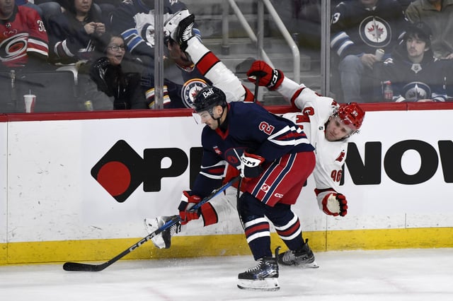 Carolina Hurricanes' Mikko Rantanen (96) is checked by Winnipeg Jets' Dylan Demelo (2) during the first period of their NHL hockey game in Winnipeg, Tuesday February 4, 2025. THE CANADIAN PRESS/Fred Greenslade