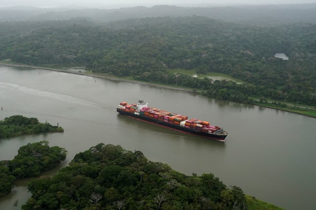 Une vue aérienne montre un cargo transitant par le canal de Panama.