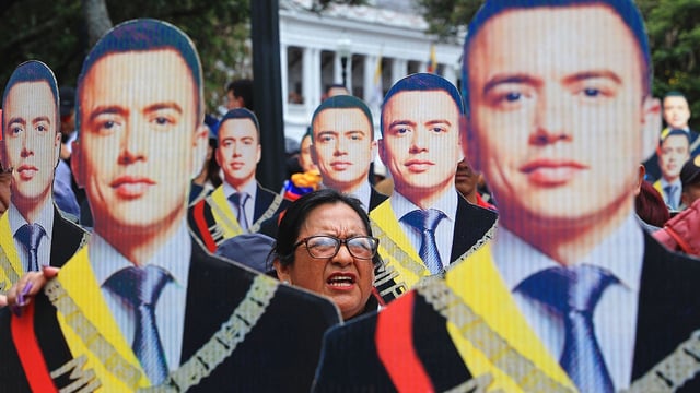 A supporter of Ecuadorian President Daniel Noboa poses amid Noboa cutouts