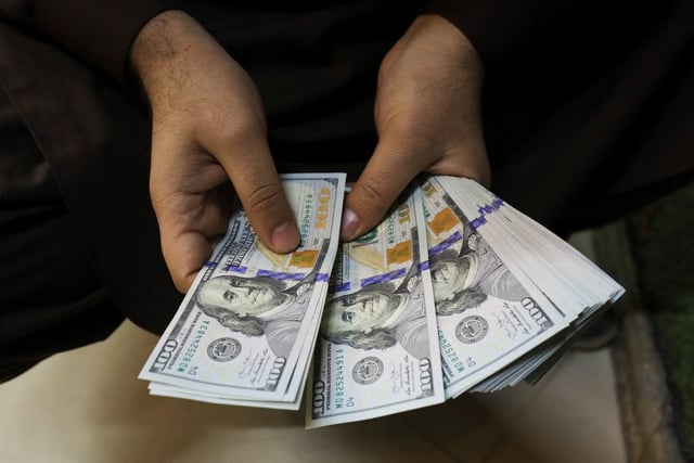 A trader counts U.S. dollar banknotes at a currency exchange booth in Peshawar, Pakistan January 25, 2023. REUTERS/Fayaz Aziz/File Photo