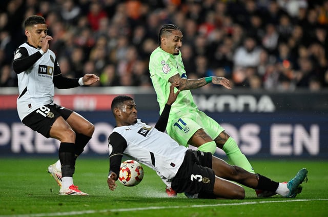 Soccer Football - Copa del Rey - Quarter Final - Valencia v FC Barcelona - Estadio de Mestalla, Valencia, Spain - February 6, 2025 FC Barcelona's Raphinha in action with Valencia's Cristhian Mosquera REUTERS/Pablo Morano