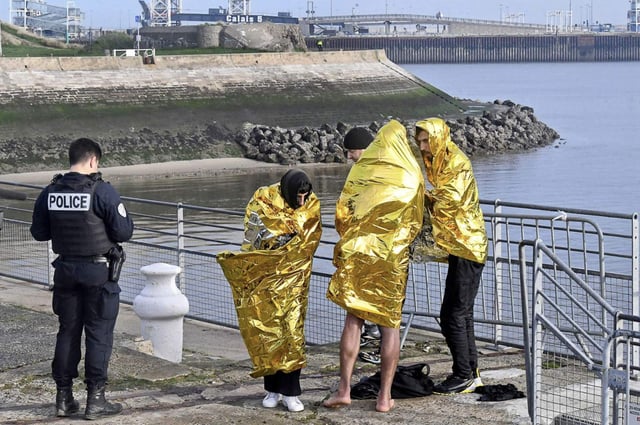 A police officer is pictured with three migrants rescued at sea during a Channel crossing to the UK in November 2022. Photo: Andia / Alamy