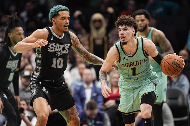 Feb 7, 2025; Charlotte, North Carolina, USA;  Charlotte Hornets guard LaMelo Ball (1) handles the ball defended by San Antonio Spurs forward Jeremy Sochan (10) during the second half at Spectrum Center. Mandatory Credit: Jim Dedmon-Imagn Images