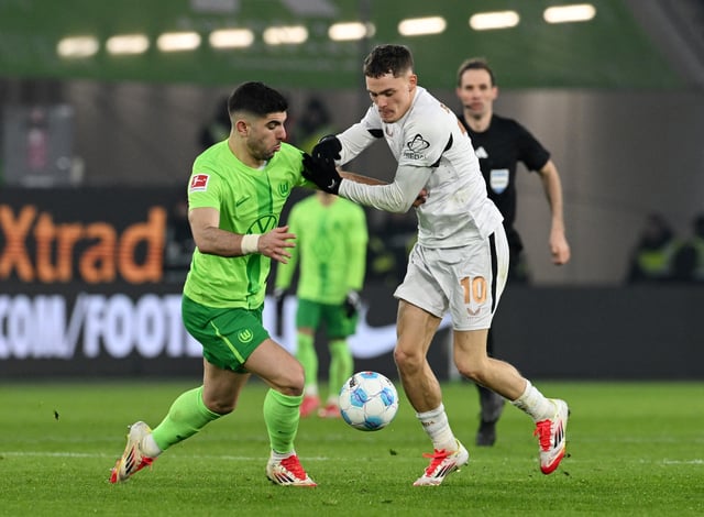 Soccer Football - Bundesliga - VfL Wolfsburg v Bayer Leverkusen - Volkswagen Arena, Wolfsburg, Germany - February 8, 2025 Bayer Leverkusen's Florian Wirtz in action with VfL Wolfsburg's Konstantinos Koulierakis REUTERS/Carmen Jaspersen