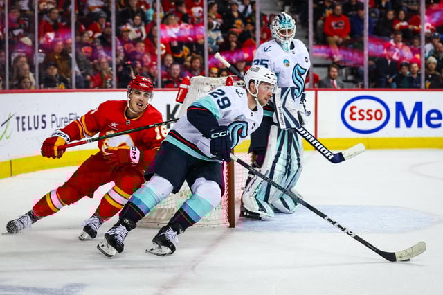 Feb 8, 2025; Calgary, Alberta, CAN; Seattle Kraken defenseman Vince Dunn (29) controls the puck against Calgary Flames center Morgan Frost (16) during the overtime period at Scotiabank Saddledome. Mandatory Credit: Sergei Belski-Imagn Images