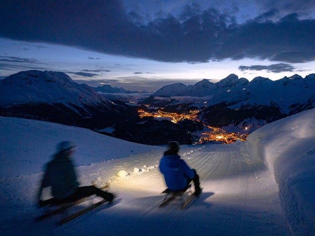 Touristen rodeln bei Nacht über eine präparierte Piste (Symbolbild).
