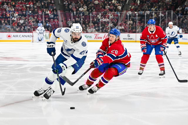 Nick Paul #20 of the Tampa Bay Lightning skates the puck against Christian Dvorak #28 of the Montreal Canadiens during the first period at the Bell Centre on January 21, 2025 in Montreal, Quebec, Canada.