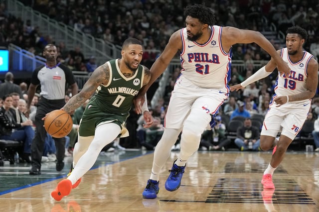 Feb 9, 2025; Milwaukee, Wisconsin, USA;  Milwaukee Bucks guard Damian Lillard (0) drives for the basket against Philadelphia 76ers center Joel Embiid (21) during the third quarter at Fiserv Forum. Mandatory Credit: Jeff Hanisch-Imagn Images