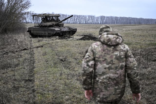 A Russian serviceman with special forces walks toward a T-80 BVM tank at a position in Kursk region, Russia.