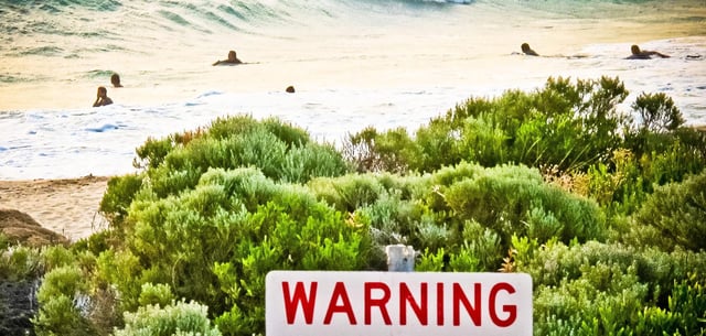 Ein Schild warnt Strandbesucher vor gesichteten Haien nah am Prevelly Beach, Australien
