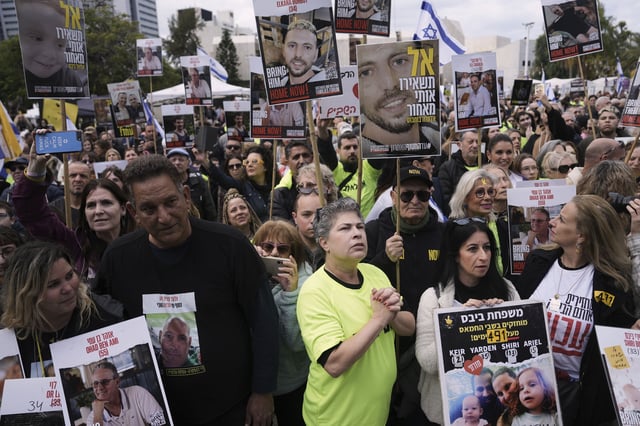 People holding posters with photos of Israelis hostages Eli Sharabi, Or Levy and Ohad Ben Ami, gather at the so-called "hostages square" waiting for their release in Tel Aviv, Israel on Saturday, Feb. 8, 2025. (AP Photo/Oded Balilty)
