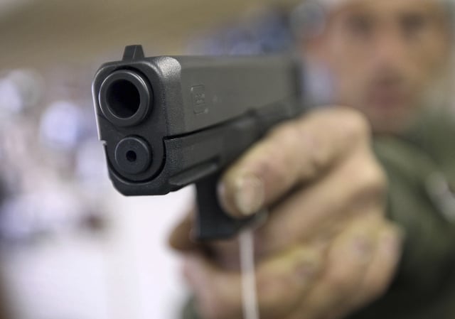 A customer tests a Glock 20 10mm handgun at the Guns-R-Us gun shop in Phoenix, Arizona, December 20, 2012. REUTERS/Ralph D. Freso/File Photo