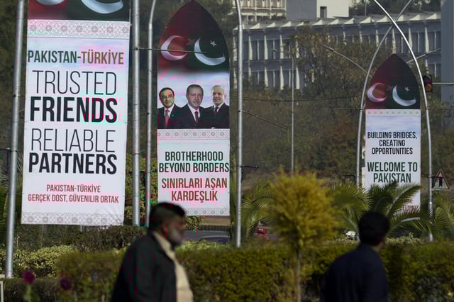 People walk past welcoming billboards with the pictures of Turkish President Recep Tayyip Erdogan, Pakistan's President Asif Ali Zardari and Prime Minister Shehbaz Sharif display on a road in Islamabad, Pakistan, Wednesday, Feb. 12, 2025. (AP Photo/Anjum Naveed)