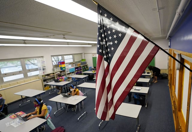 FILE - An American flag hangs in a classroom as students work on laptops in Newlon Elementary School, in Denver, Aug. 25, 2020. (AP Photo/David Zalubowski, File)