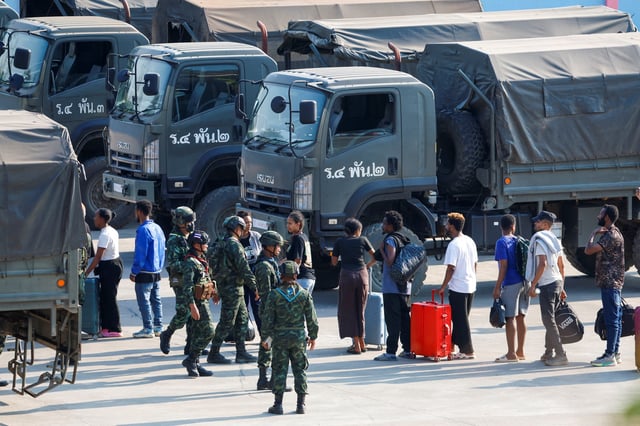 Multinational victims of scam centers, who were tricked or trafficked into working in Myanmar, carry their belongings and walk in line to get on army trucks after they were sent to Thailand, in Phop Phra District, Tak province, Thailand February 12, 2025. REUTERS/Krit Phromsakla Na Sakolnakorn