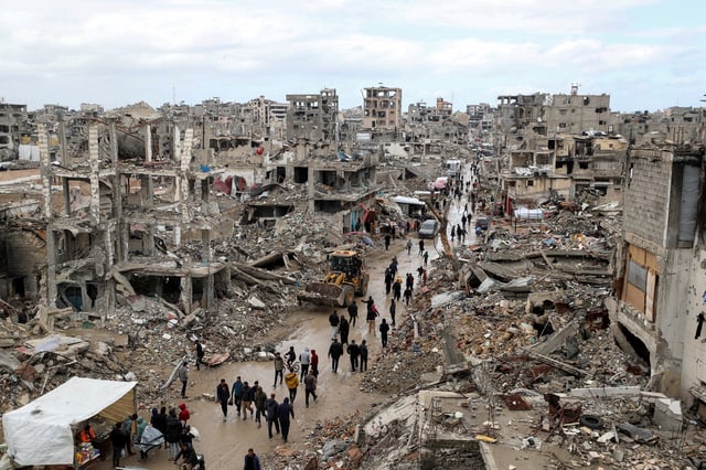 Palestinians walk past the rubble of buildings destroyed during the Israeli offensive, on a rainy day, amid a ceasefire between Israel and Hamas, in Gaza City February 6, 2025. REUTERS/Dawoud Abu Alkas/File Photo