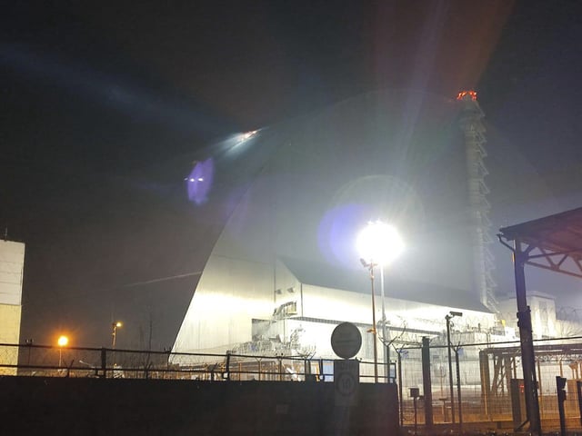In this photo provided by the Ukrainian Emergency Service, a searchlight illuminates a hole in the roof of a damaged sarcophagus, that covers the destroyed 4th reactor of Chernobyl nuclear power plant, following a Russian drone attack in Chernobyl, Ukraine, Friday, Feb. 14, 2025. (Ukrainian Emergency Service via AP)