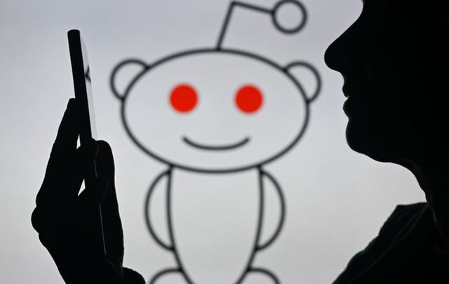 An image of a woman holding a cell phone in front of the Reddit logo displayed on a computer screen, on April 29, 2024, in Edmonton, Canada.