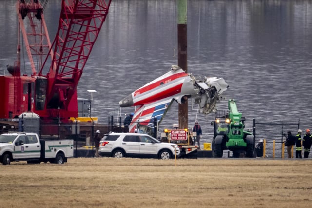 A crane offloads a piece of wreckage from a salvage vessel onto a flatbed truck, near the wreckage site in the Potomac River of a mid-air collision between an American Airlines jet and a Black Hawk helicopter, at Ronald Reagan Washington National Airport, Wednesday, Feb. 5, 2025, in Arlington, Va. (AP Photo/Ben Curtis)