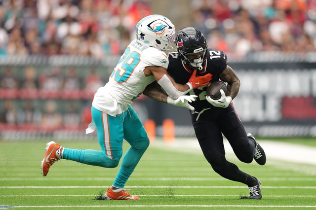 HOUSTON, TEXAS - DECEMBER 15: Kendall Fuller #29 of the Miami Dolphins tackles Nico Collins #12 of the Houston Texans during the first half at NRG Stadium on December 15, 2024 in Houston, Texas.