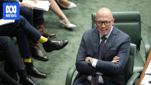 Dutton smiles, sitting in parliament with his arms crossed