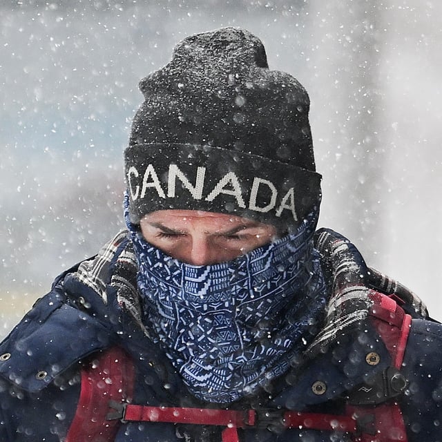A person covers up during a snowstorm in Montreal, Sunday, February 16, 2025. THE CANADIAN PRESS/Graham Hughes