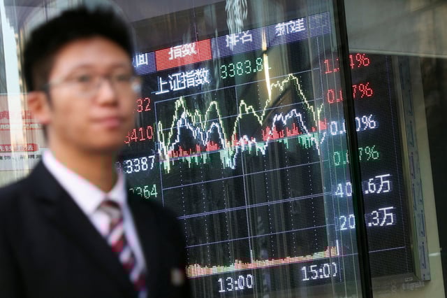 A man walks past a brokerage house with a display board showing the Shanghai Composite Index and other stock information, in Beijing, China November 6, 2024. REUTERS/Florence Lo/File Photo