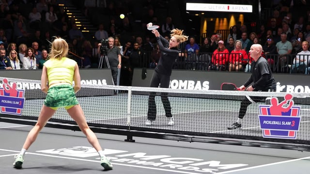 Steffi Graf (C) returns a volley as she and Andre Agassi play play a doubles match against Eugenie Bouchard (L) and Andy Roddick.