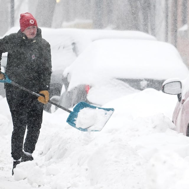 A person clears snow from around a car during a snowstorm in Montreal, Sunday, February 16, 2025. A winter storm continues to strengthen in parts of Ontario and Quebec on Sunday as heavy snowfall is expected to blanket the provinces with a second big storm in just four days. THE CANADIAN PRESS/Graham Hughes