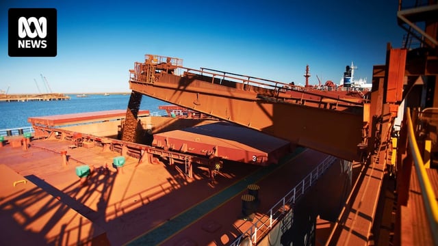 A wide shot of iron ore being loaded onto a ship in Port Hedland.