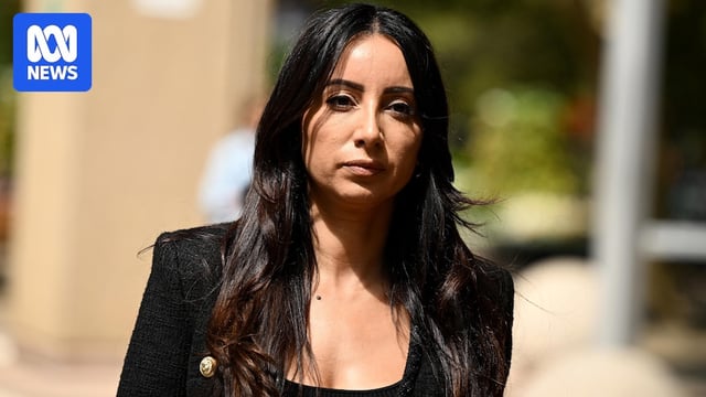 A woman with long dark hair wearing a dark jacket