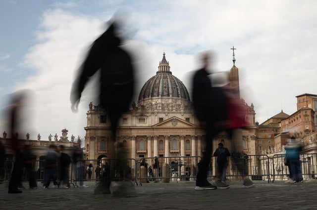 Des personnes marchent près de la place Saint-Pierre alors que le pape François est admis pour continuer son traitement d’une infection des voies respiratoires, au Vatican, le 18 février 2025.