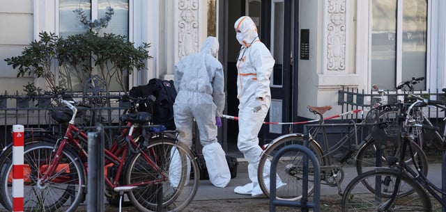 Mitarbeiterinnen der Spurensicherung der Polizei stehen vor dem Mehrfamilienhaus, wo in einer Wohnung die tote Frau gefunden wurde