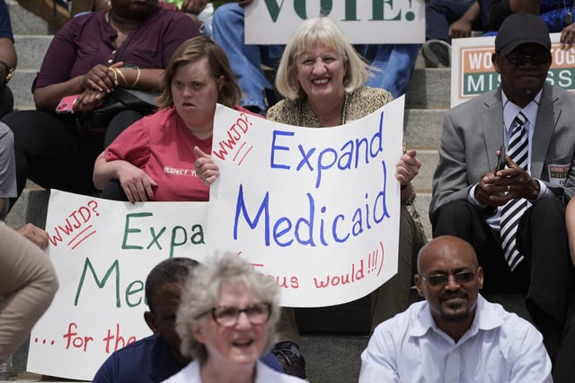 A mother and daughter hold homemade support signs at the Mississippi Medicaid Expansion Rally at the Mississippi State Capitol in Jackson, Tuesday, April 16, 2024.