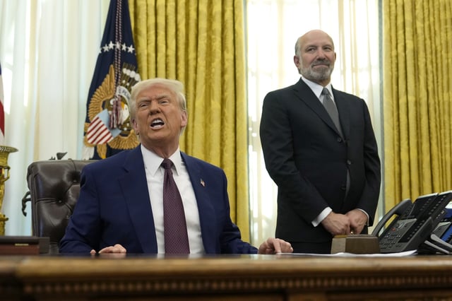President Donald Trump speaks to reporters as Commerce Secretary nominee Howard Lutnick listens after Trump signed an executive order in the Oval Office of the White House, Thursday, Feb. 13, 2025, in Washington. (AP Photo/Ben Curtis)