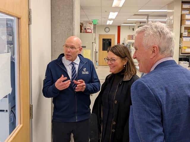 Fred Hutch Cancer Center oncologist Dr. Peter Nelson, left, explains his lab's research to Congresswoman Suzan DelBene as Dr. Tom Lynch, Fred Hutch president and director looks on. (GeekWire Photo / Lisa Stiffler)