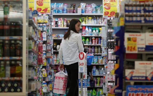 A shopper looks at items as she queues in line for the cashier at a discount store in Tokyo September 30, 2014. REUTERS/Yuya Shino/File Photo
