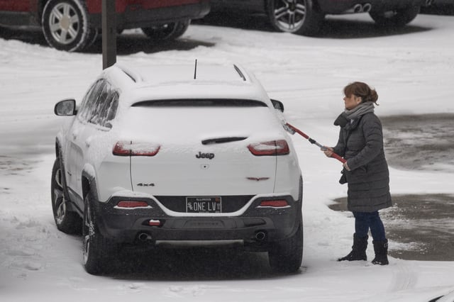 A woman clears snow from her vehicle parked in a downtown lot as a winter storm passes over the city on February 12, 2025 in Chicago, Illinois. The storm is part of a weather system passing over the central and eastern United States, triggering winter storm warnings in 14 states.