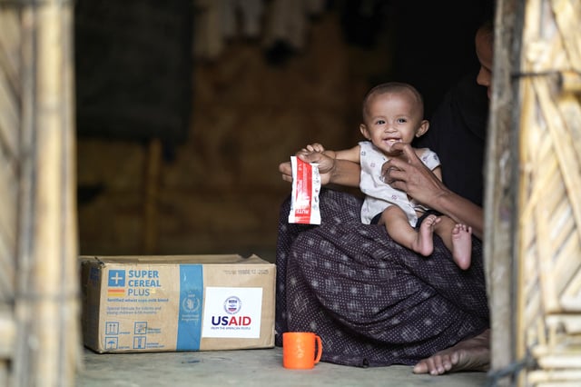 A Rohingya woman feeds nutrition supplements that have been provided by USAID, to a child at a refugee camp in Cox's Bazar, Bangladesh, February 11, 2025. REUTERS/Ro Yassin Abdumonab/File Photo