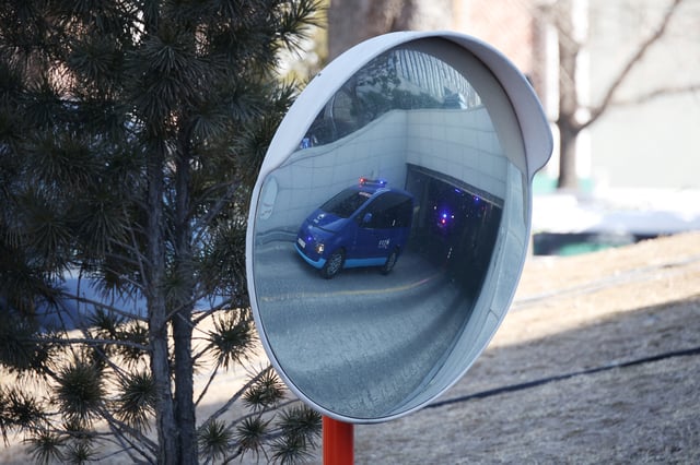 A vehicle carrying South Korea's impeached President Yoon Suk Yeol is reflected on a convex traffic mirror as it leaves the Constitutional Court in Seoul, South Korea, February 18, 2025.   REUTERS/Kim Hong-Ji